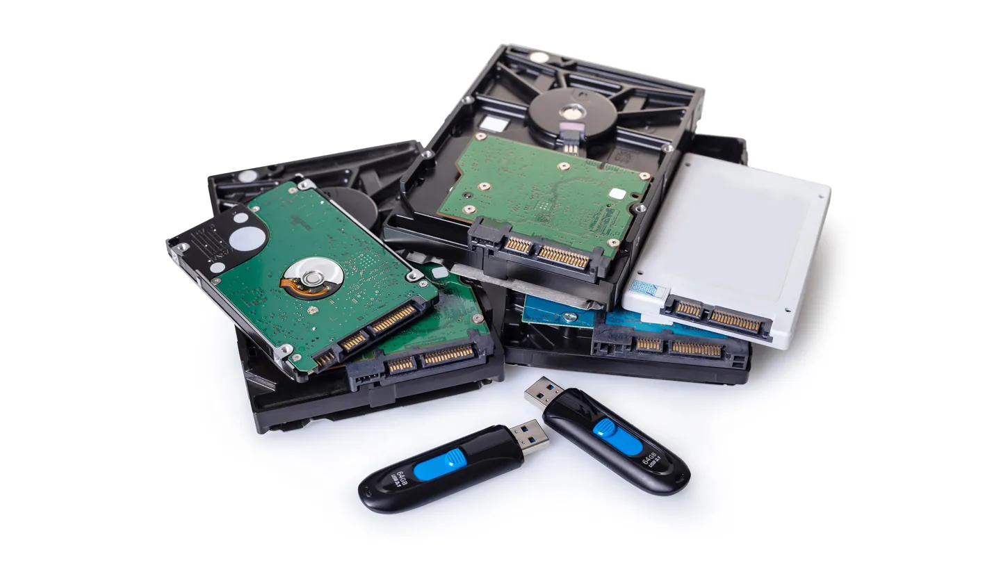 Mehrere Festplatten und USB-Sticks auf weißem Grund.